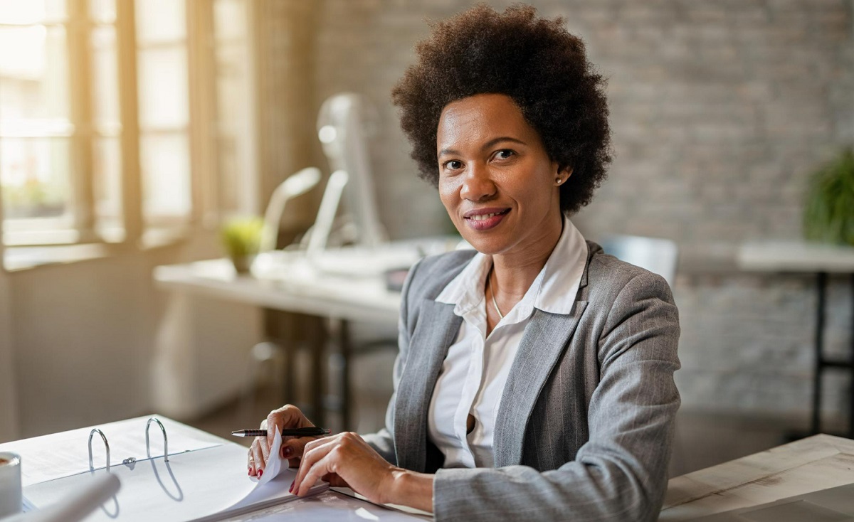 black-smiling-businesswoman-analyzing-financial-reports-while-working-in-the-office-and-looking-at-the-camera.jpg