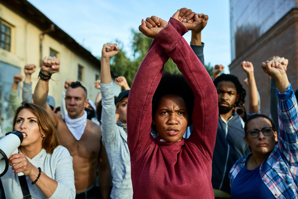 black-woman-with-clenched-fists-above-her-head-protesting-with-group-of-people-on-the-streets.jpg