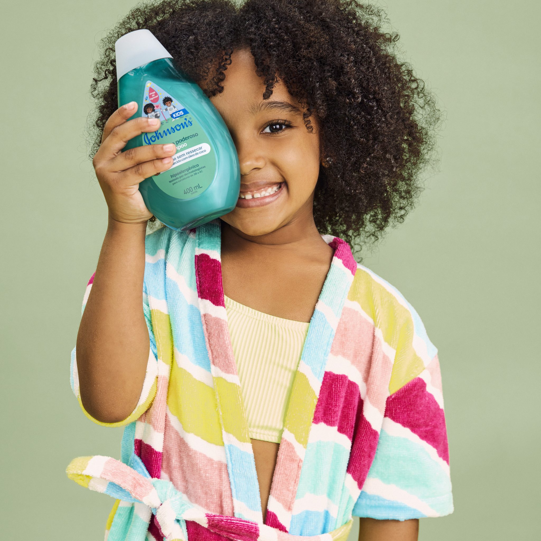 Criança negra com cabelos crespos segurando um dos produtos da linha ‘Blackinho Poderoso’ 