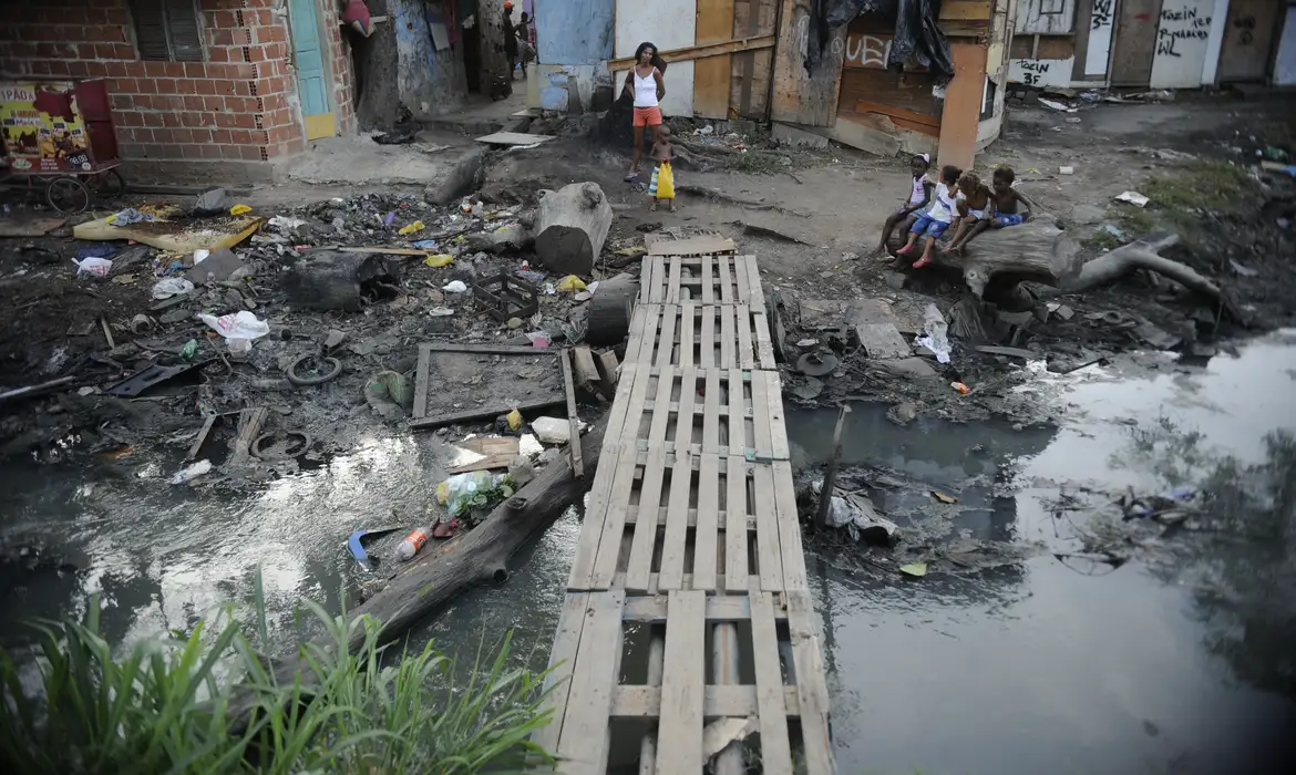 Imagem esgoto em céu aberto no meio de casas e moradores 